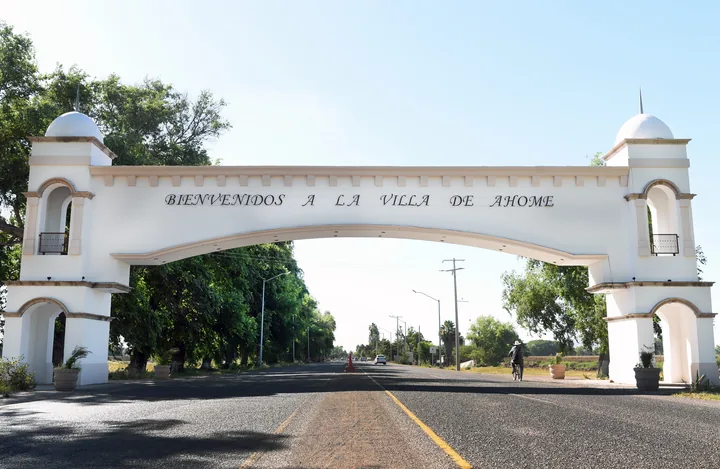 Arco de bienvenida blanco con torres y cúpulas sobre la carretera de acceso a la Villa de Ahome