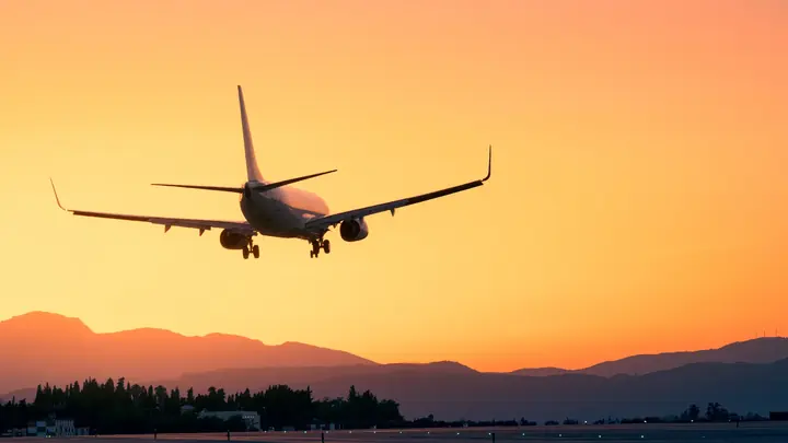 Avión comercial aterrizando al atardecer